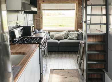 Interior of tiny house on Hudson, Colorado, horse farm with a picture window and a comfy gray couch