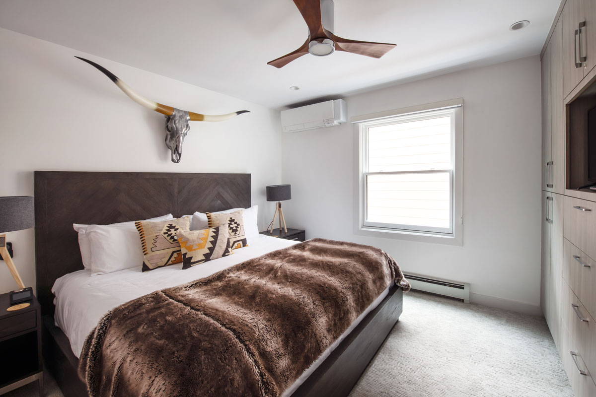 A bedroom at The Gant featuring a king bed with a plush chocolate-colored headboard and comforter along with Western decor