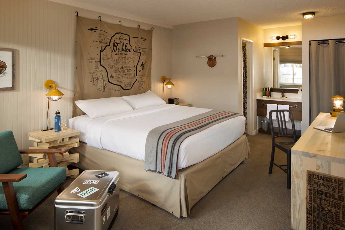 A guest room at the Basecamp Hotel in Boulder. The room has an adventure theme with a canvas map and stickered ice chest.