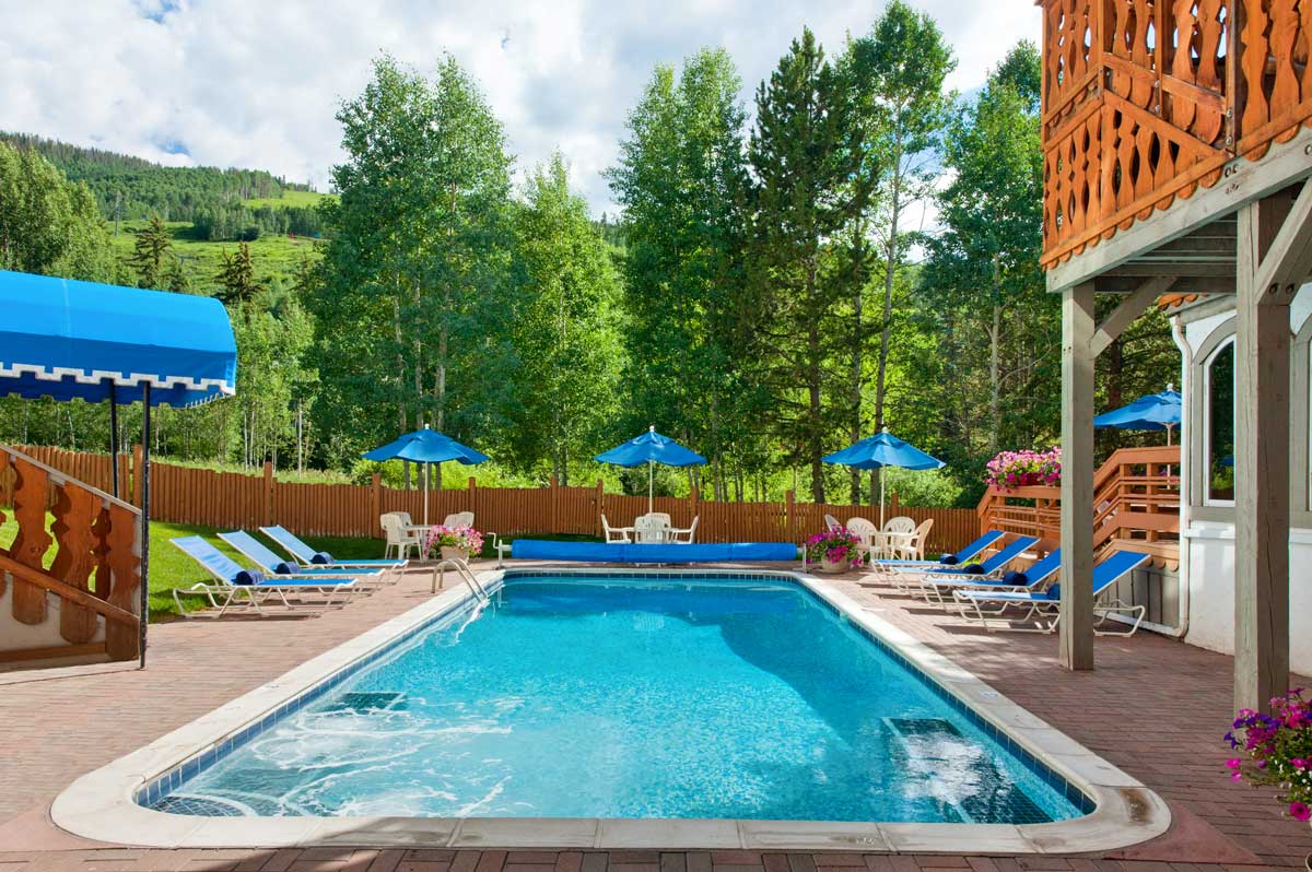 A summer view of Christiania at Vail's outdoor pool with Vail Mountain in the background