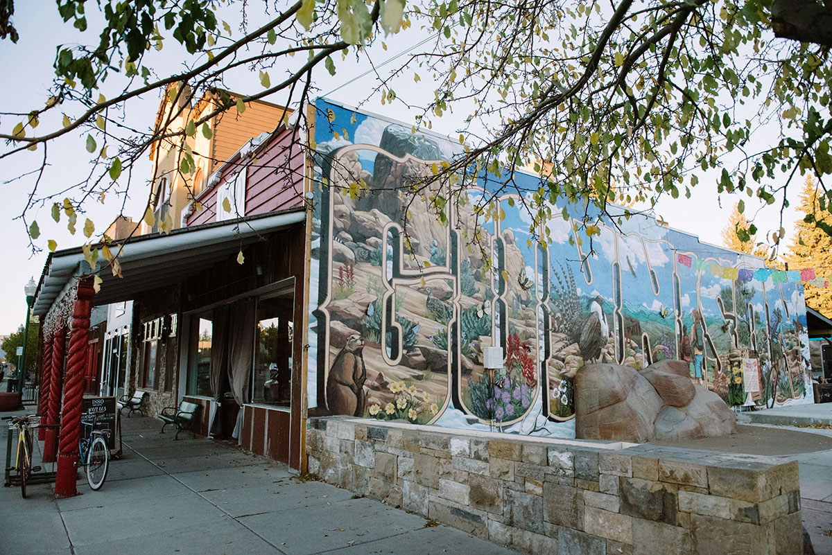 Mural with animals and mountains that reads "Gunnison" on the side of a building