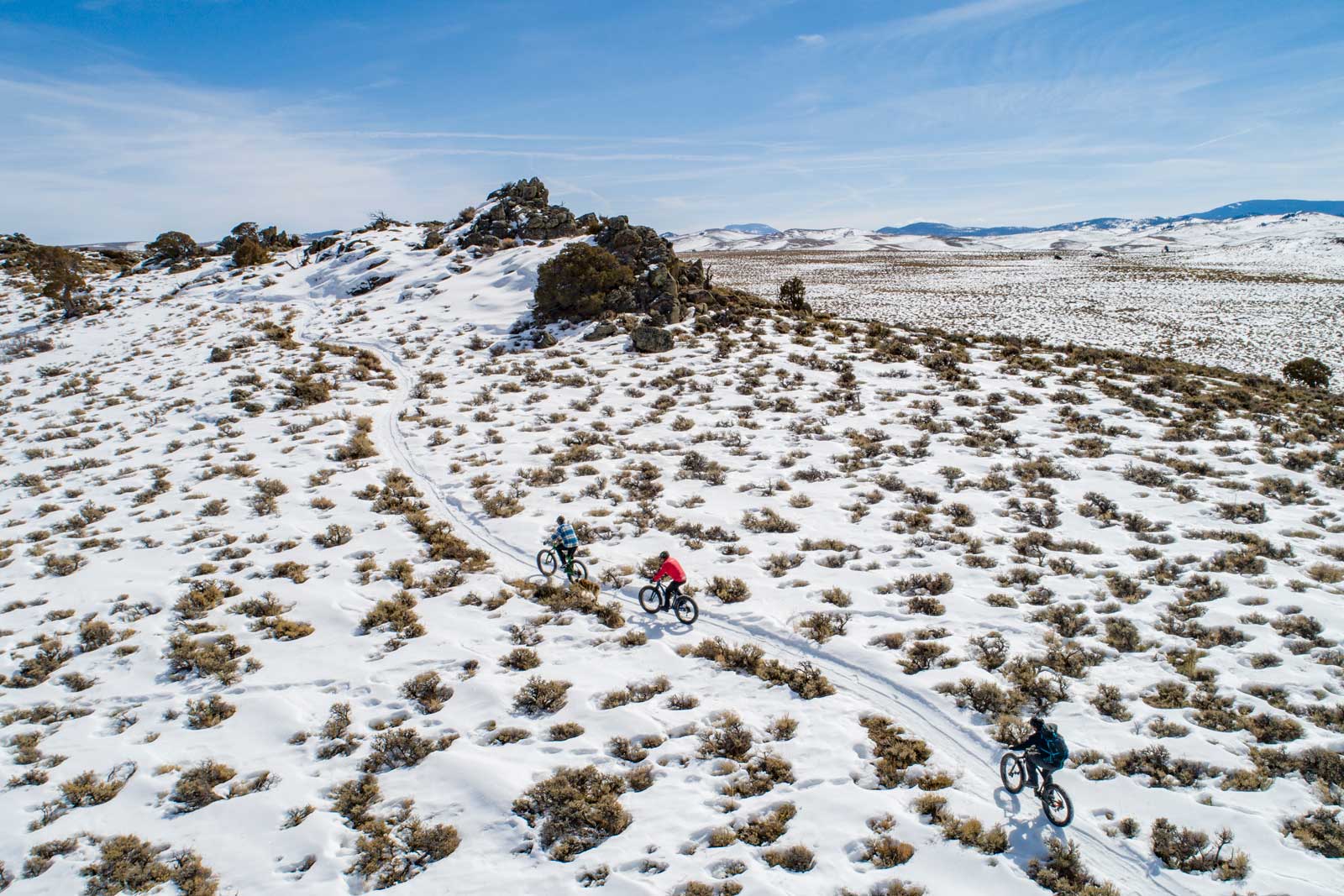 Fat-bike riders on a trail through a snowy recreation area in Gunnison