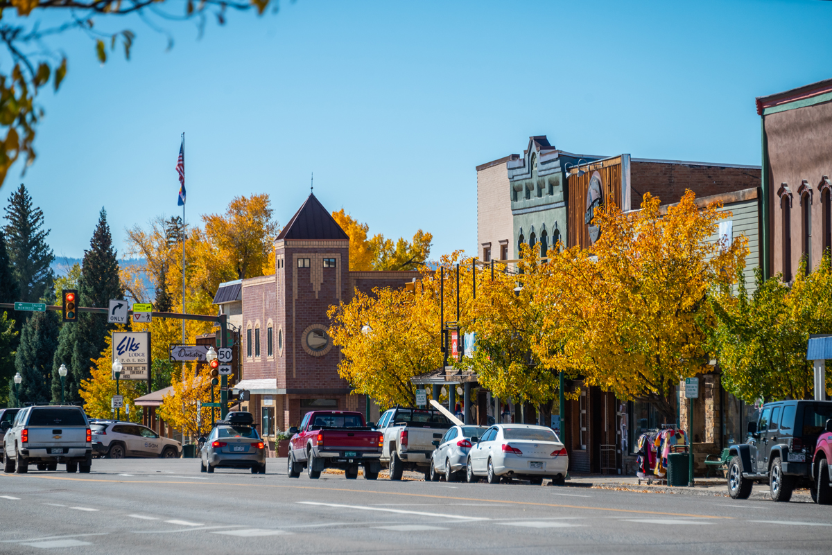 Victiorian buildings flanked with trees with orange autumn leaves in downtown Gunnison Colorado