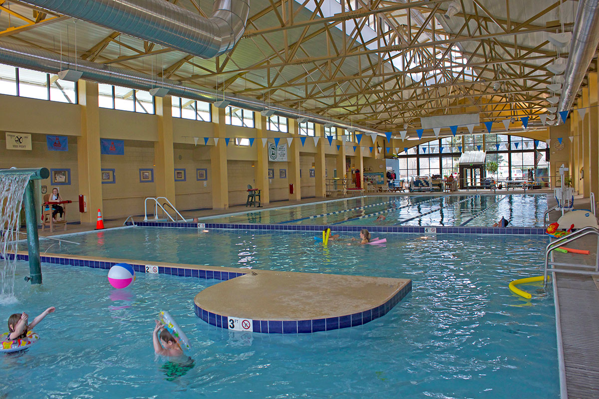 Large indoor pool with lap lanes and a woman floating on foam pool noodles