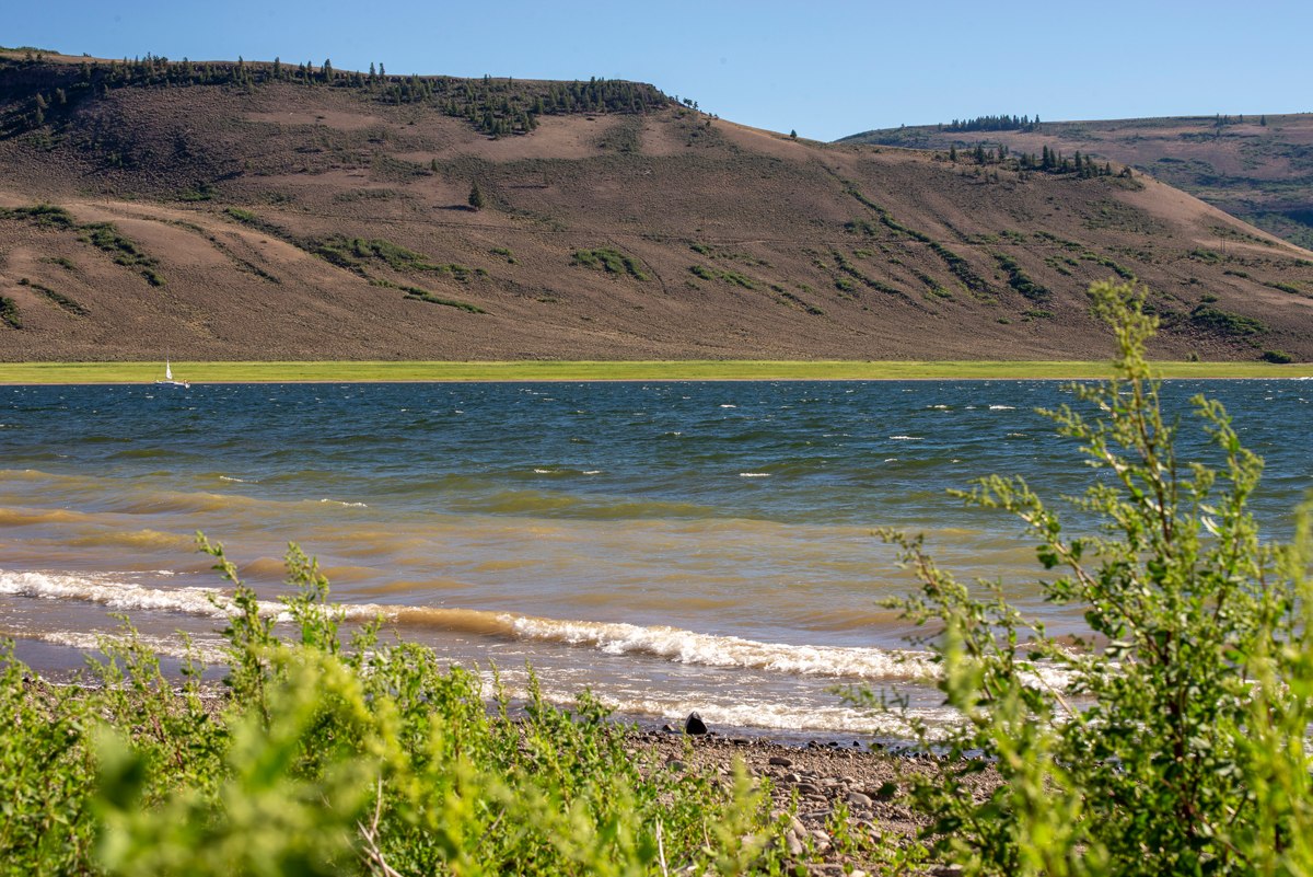 The waters of Blue Mesa Reservoir lap a shore of rock and sand in Gunnison, Colorado