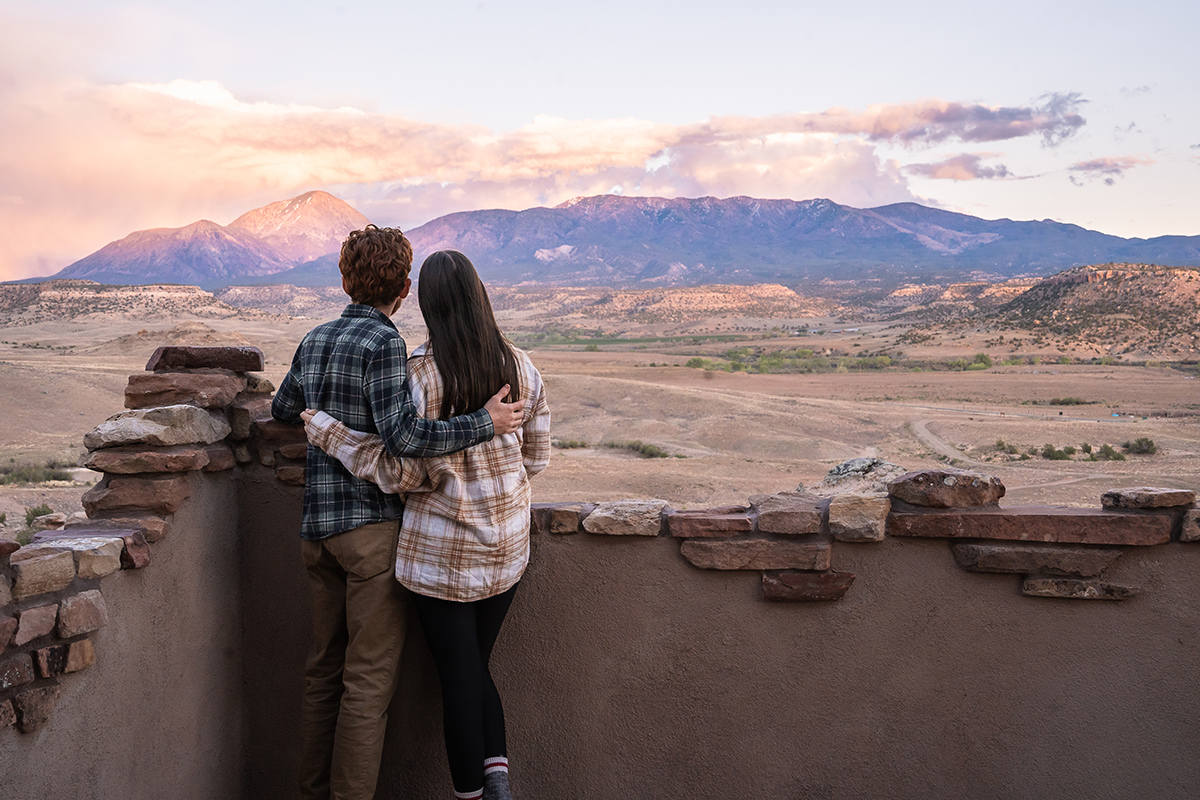 Two people, both wearing plaid-pattern flannel shirts, hold each other and admire the nearby mountains from the Sky Tower at Canyon of the Ancients Guest Ranch near Cortez, Colorado.