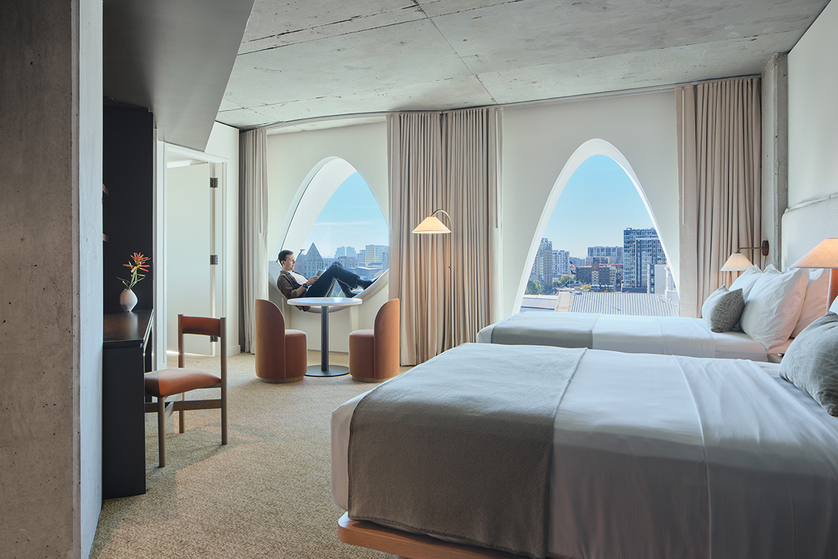 A person reads a book in the curved window seat at Populus. Outside the window are stunning views of Denver's cityscape.