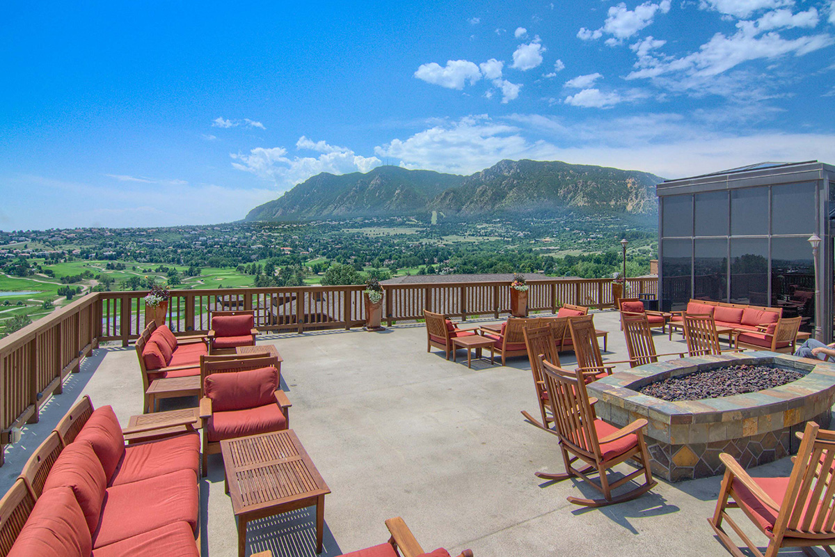 A terrace at Cheyenne Mountain Resort offers stunning mountain views and plenty of red-cushioned seating.