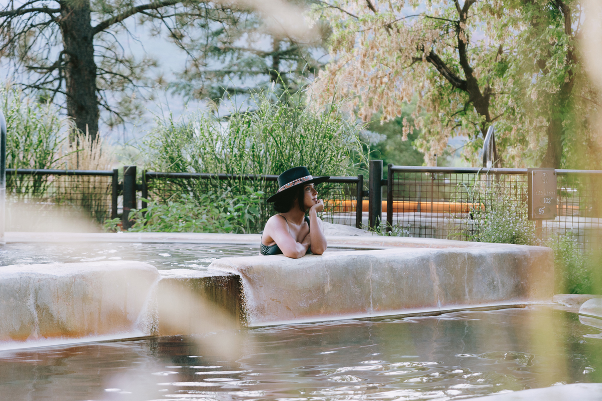 A person wearing a black cowboy hat leaning on their elbow on the side of a hot-springs pool in Durango Colorado