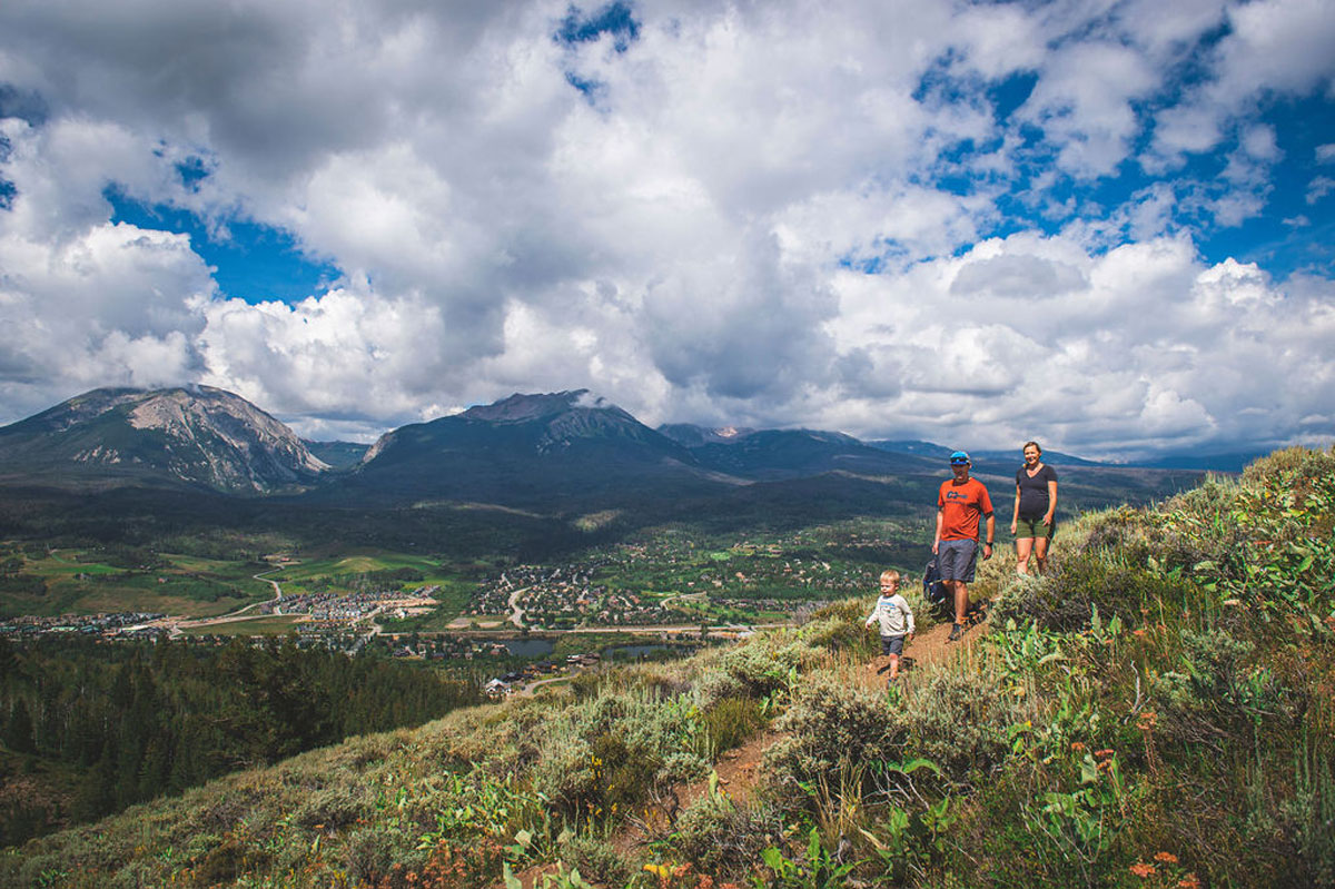 Family hiking though lush greenery along the Angler Mountain Trail in SIlverthorne Colorado