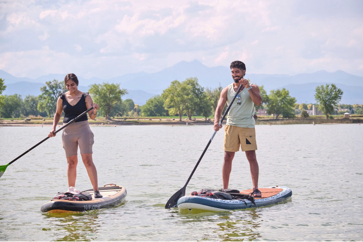 Two people stand-up paddleboarding over calm water.