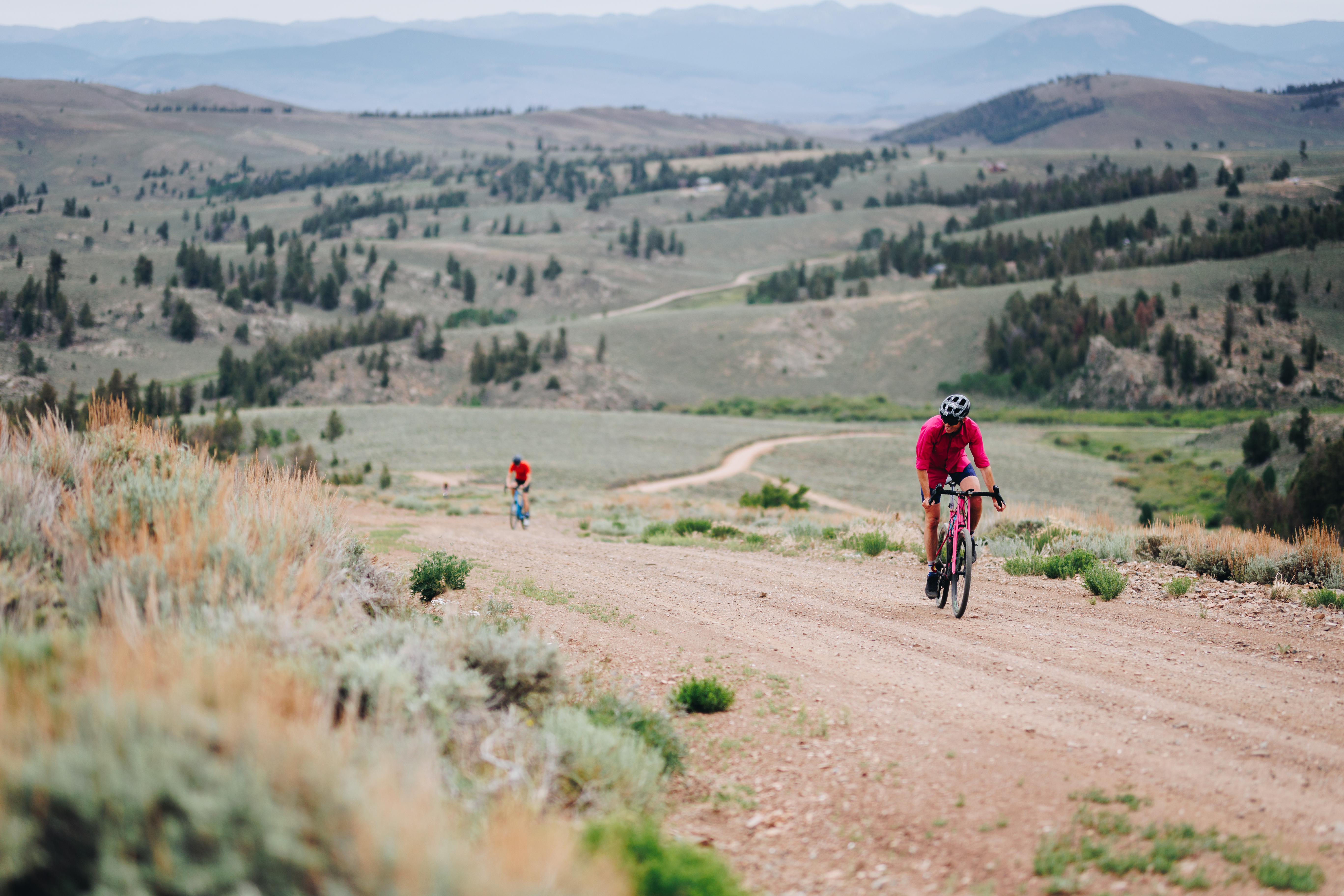 A biker rides on Colorado roads in Gunnison, cutting  through a landscape of rolling hills dotted with sagebrush.