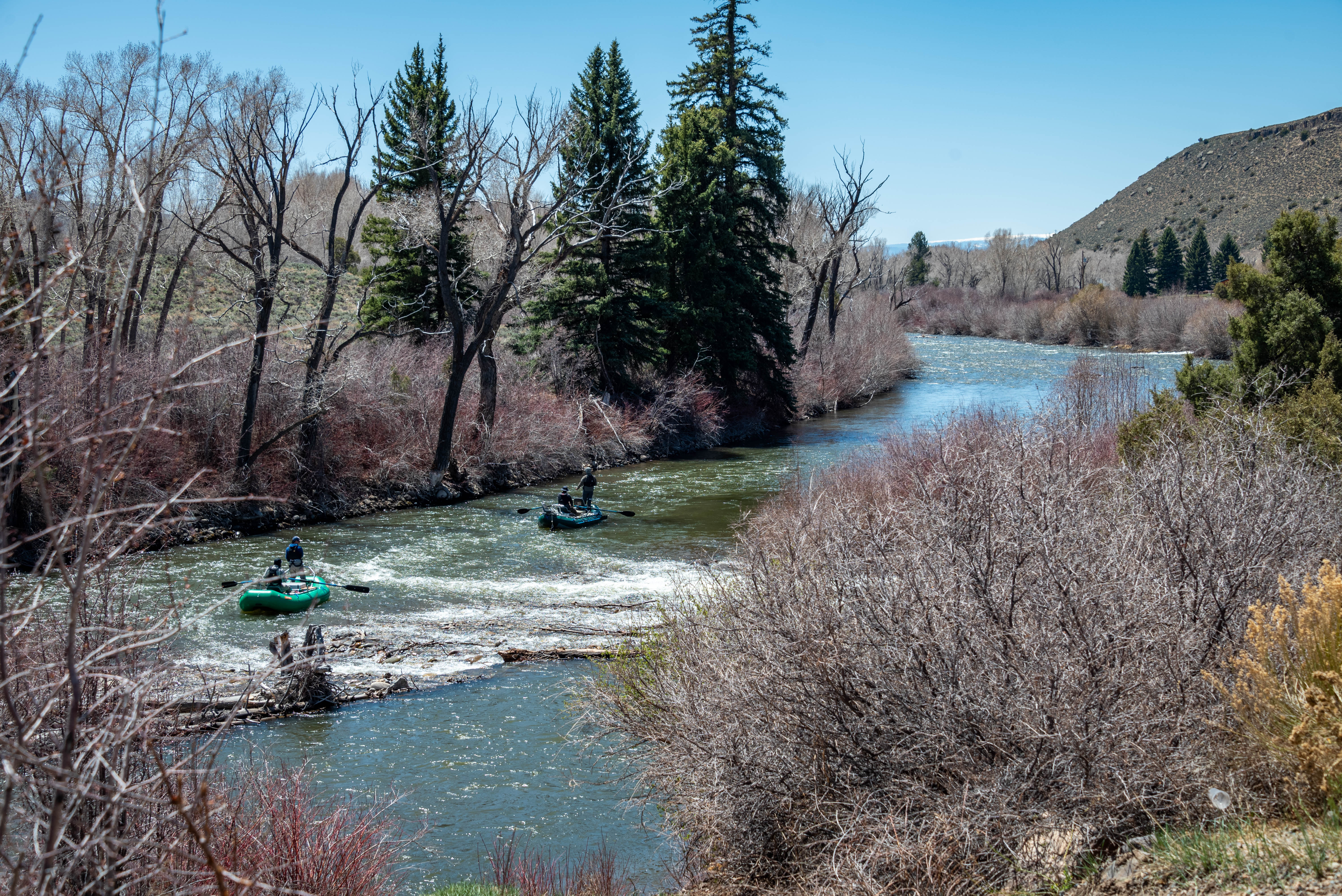 Two people whitewater raft down a river in Gunnison, Colorado.