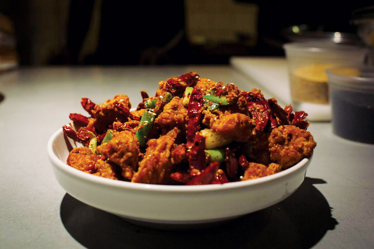 A spicy chicken dish peppered with peppers in a white bowl