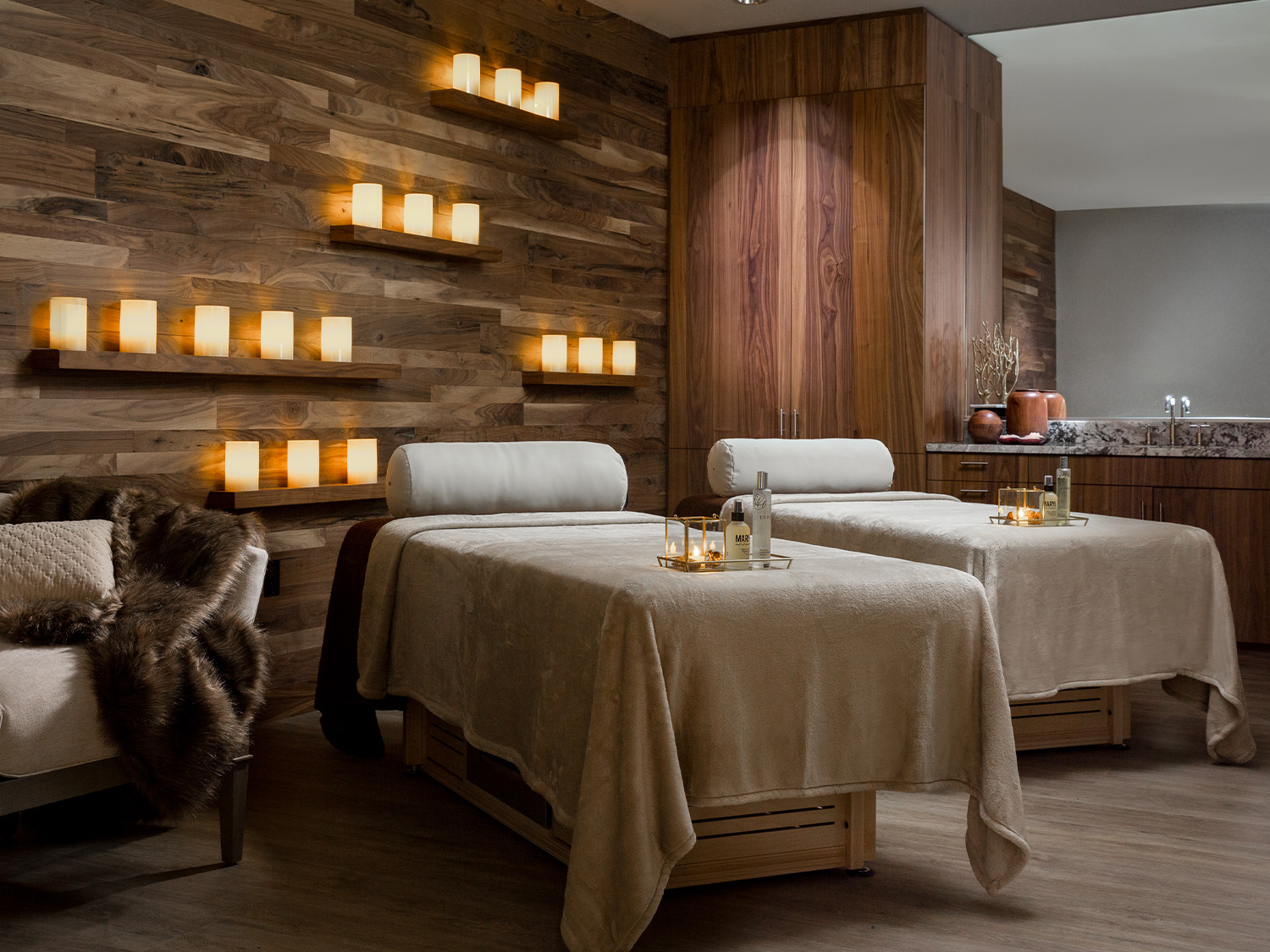 Two spa beds sit ready to welcome patrons while candles flicker on shelves in the background at Relâche Spa at Gaylord Rockies Resort & Convention Center in Aurora, Colorado. 