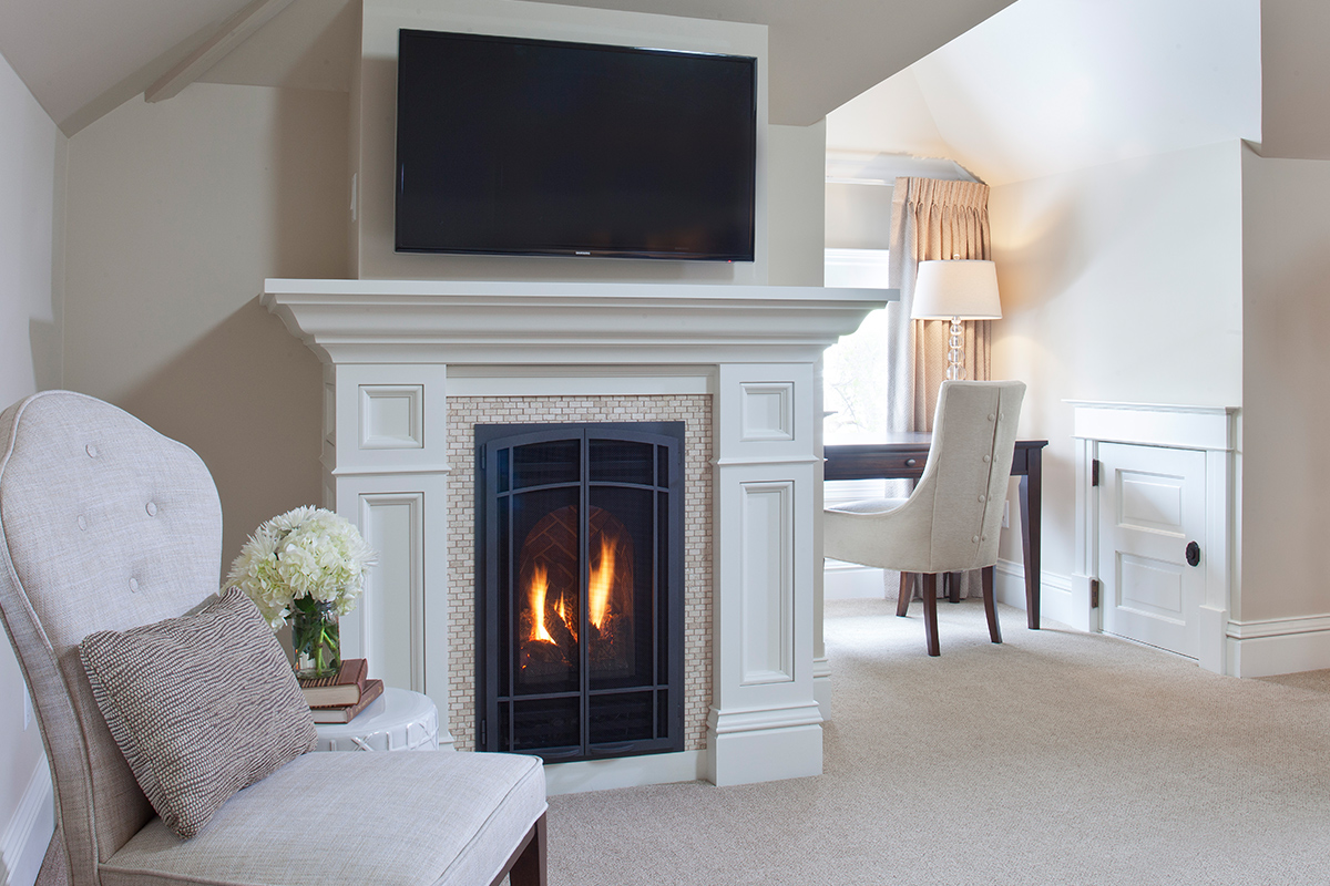 A stately fireplace with a crackling fire, stands in a modern beige and white decorated room at Edwards House in Fort Collins.