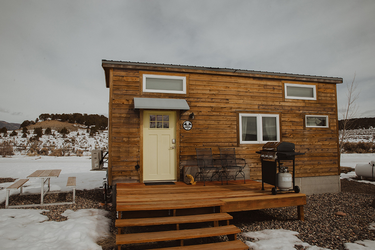 A layer of snow surrounds a log-cabin style tiny home at Trail and Hitch in Meeker, Colorado.