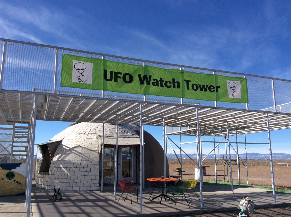 A silver dome with a green banner over head reading "UFO Watchtower" at a popular UFO-spotting site in Alamosa Colorado