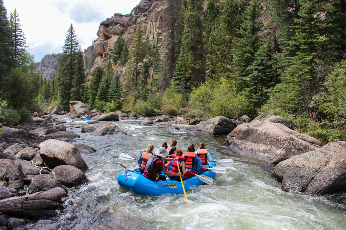 People in a blue raft navigating rushing water on the Upper Taylor River.