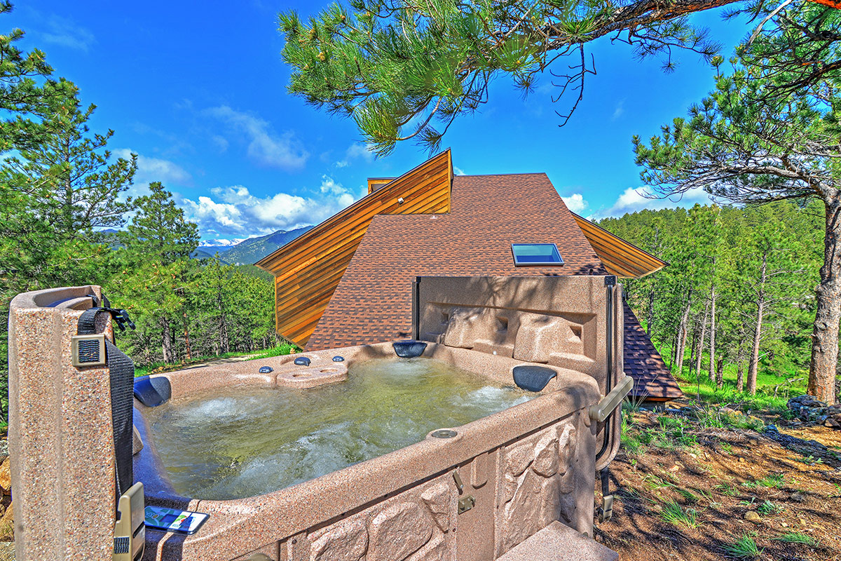 A rooftop hot tub at Barret House near Boulder, Colorado, offers stunning views of the mountains, forest and clear sky.