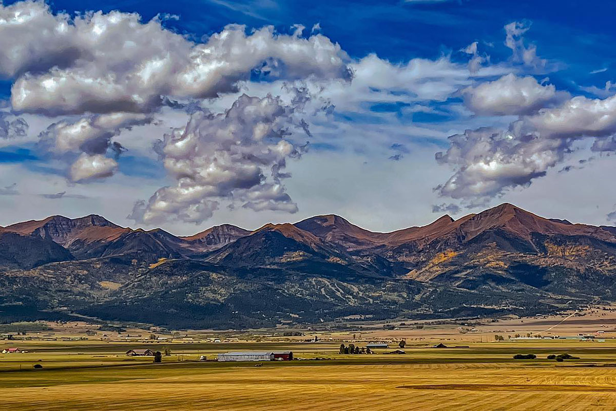 Daylight far away views of a wide open valley with mountains as the backdrop in Silver Cliff, Colorado.