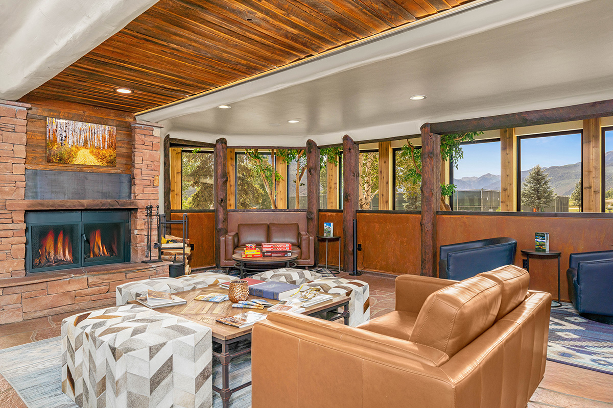 A common area at the Chipeta Lodge Resort + Spa features a burning fireplace, cushy arm chairs, games and breathtaking mountain vistas.