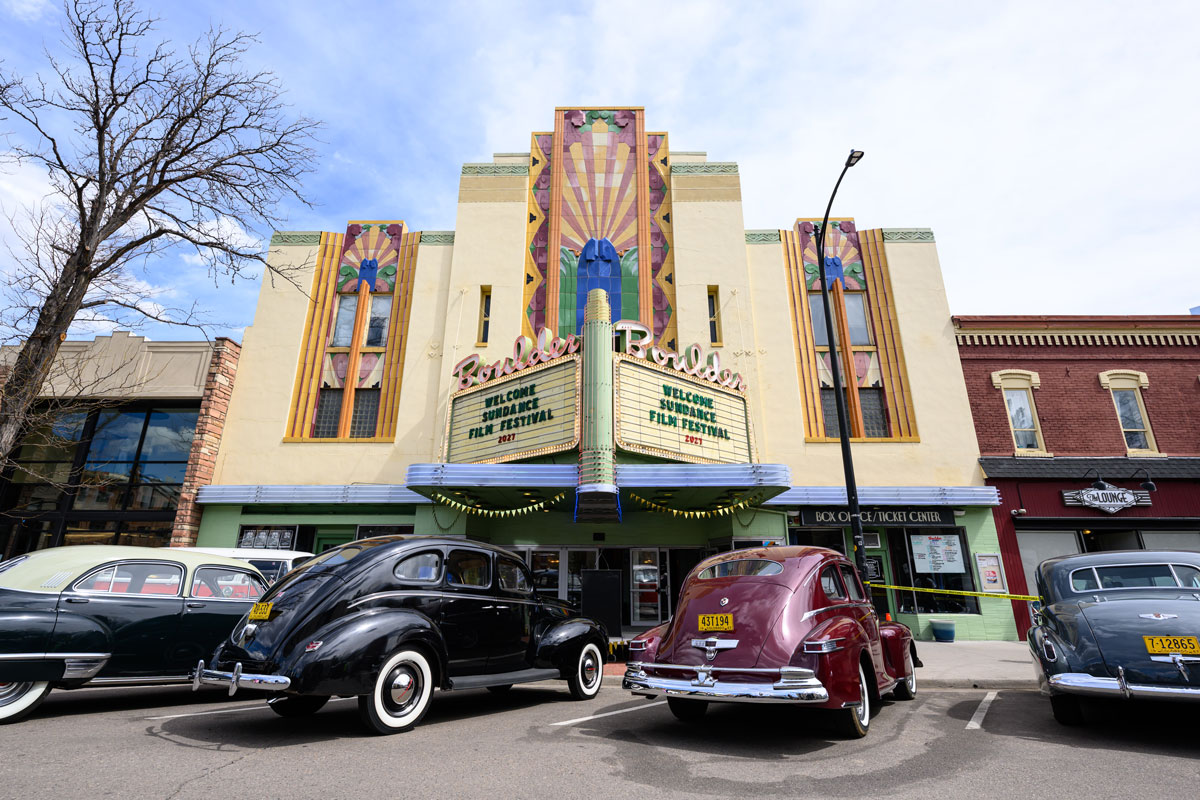 Outside view of the historic Boulder Theater with vintage cars lined up and parked in the front in Boulder, Colorado.