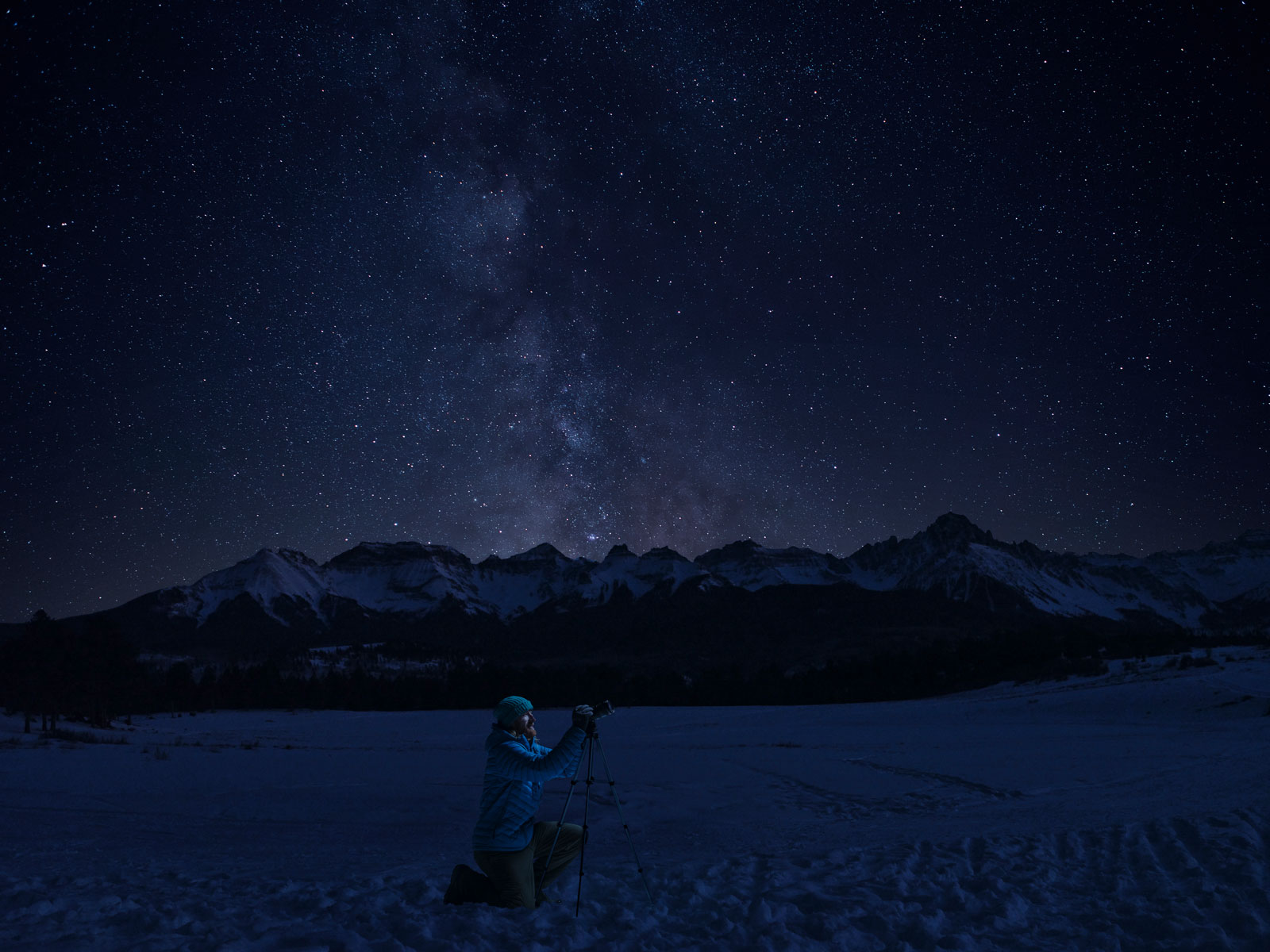 A man focuses a telescope under Top of the Pines night skies