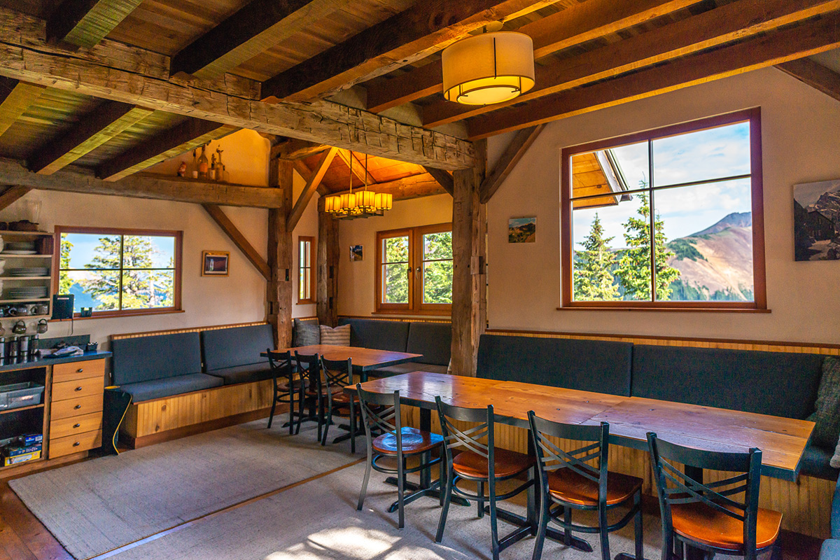 Enjoy company, food and good vibes at the communal, lodge-style dining area fitted with banquets, exposed wooden beams and full meal service at OPUS Hut.