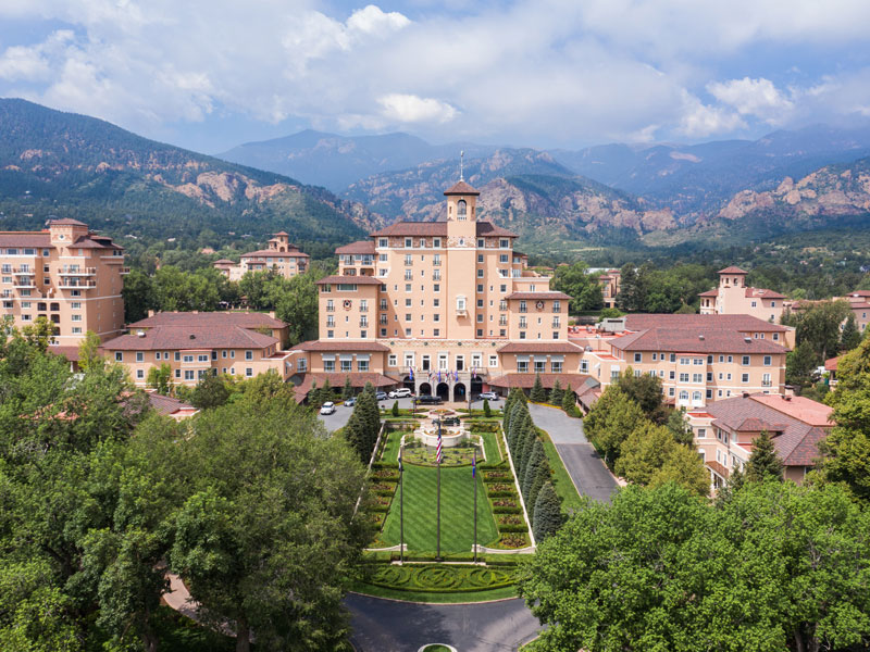 The Broadmoor resort in Colorado Springs with manicured gardens and the Rocky Mountains in the background.