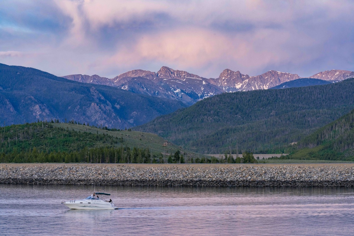 A boat on the water with mountains and hills in the background near Granby, Colorado.