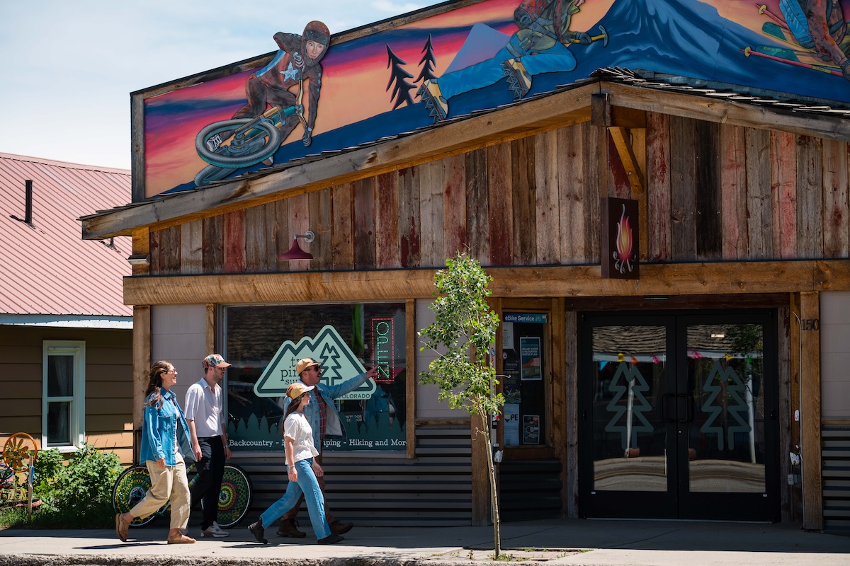Adults walking past the entrance of an outdoor gear shop in Granby, Colorado.