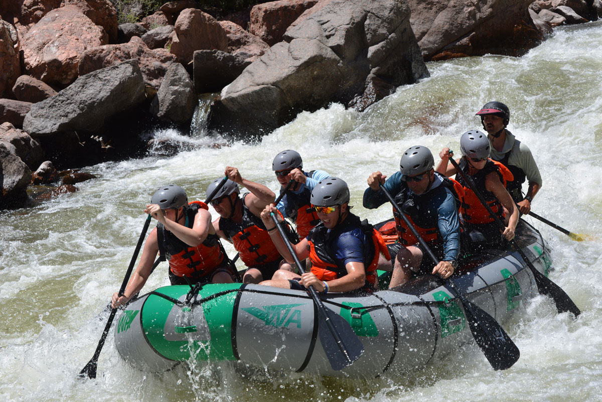 Whitewater rafters paddle through rapids in the Royal Gorge near Cañon City, surrounded by rocky canyon walls.