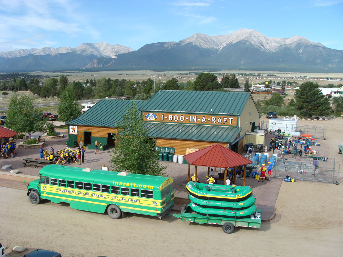 Wilderness Aware Rafting headquarters in Buena Vista with rafts, gear and shuttle bus set against a mountain backdrop.
