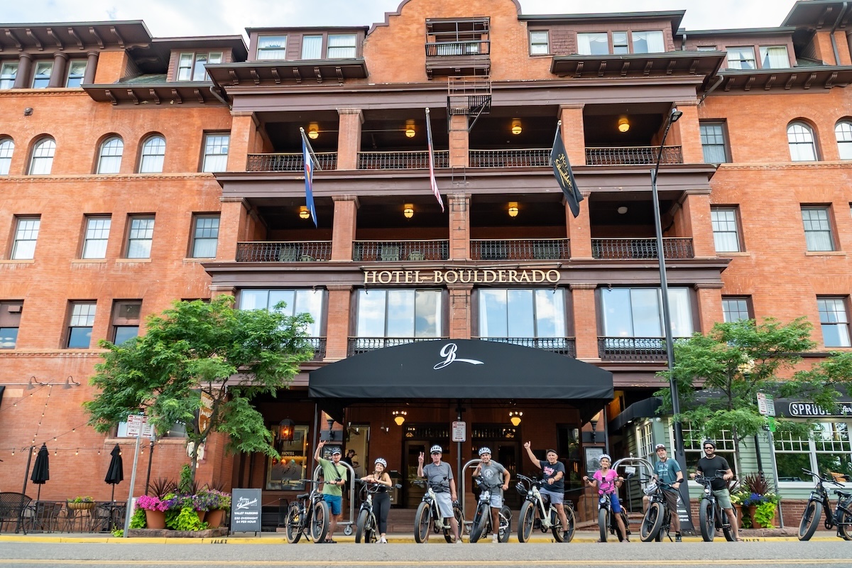 Group of e-bike riders posing outside Hotel Boulderado in Boulder, Colorado during a Ride Colorado tour.