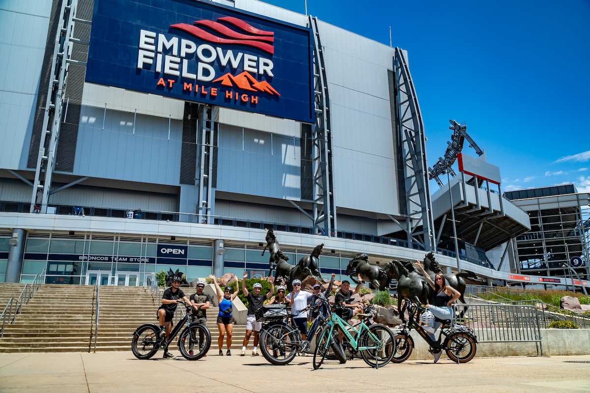 E-bike riders posing outside Empower Field at Mile High in Denver, Colorado.