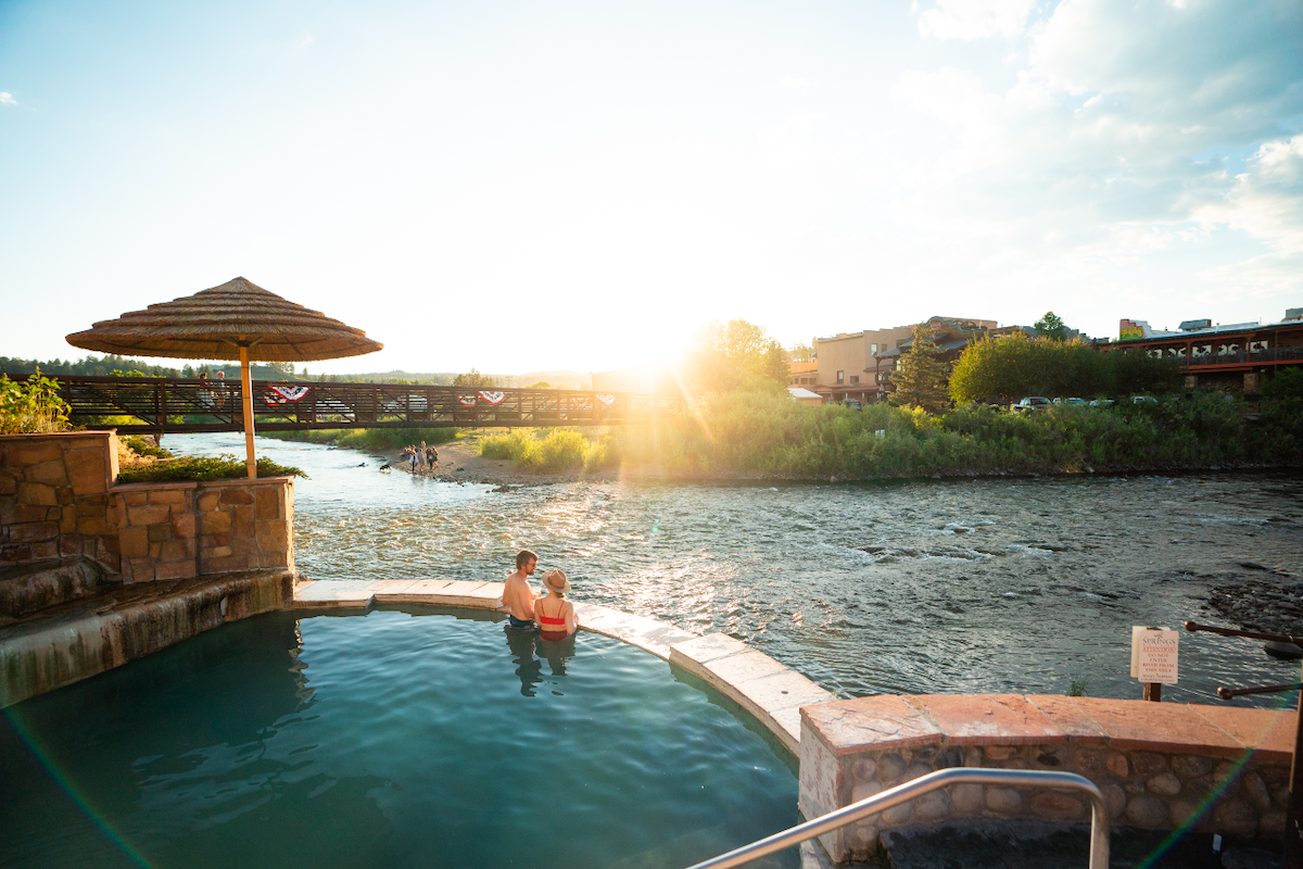 A couple soaks in a steaming mineral spring as the sun sets at The Springs Resort in Pagosa Springs, Colorado.