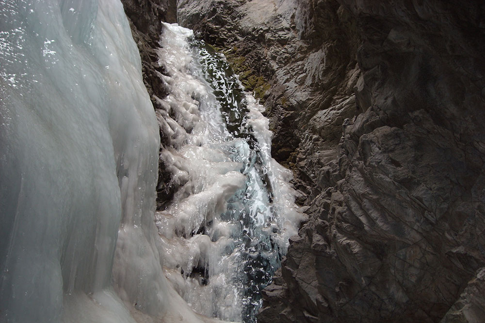 Water rushes down Zapata Falls, one side of the rock is covered in ice