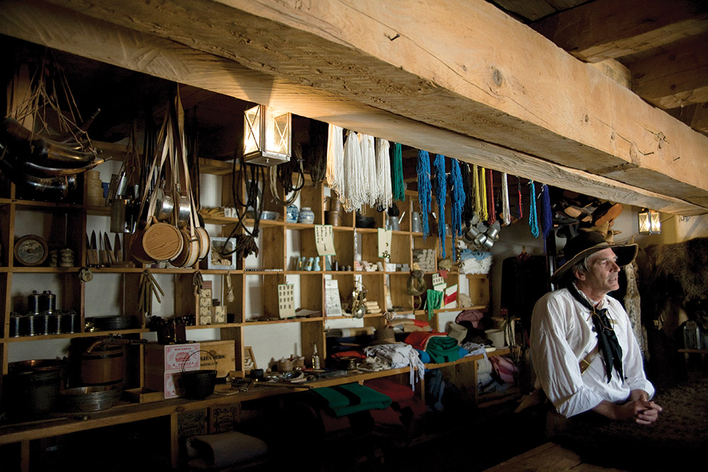 A person in a white shirt sits by a bar stacked with bottles at Bent's Old Fort on the Santa Fe Trail in Colorado.