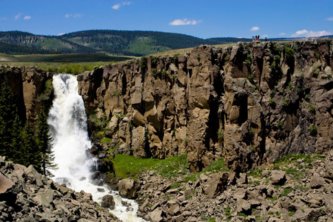 Water rushes down Clear Creek Falls with blue skies in the background