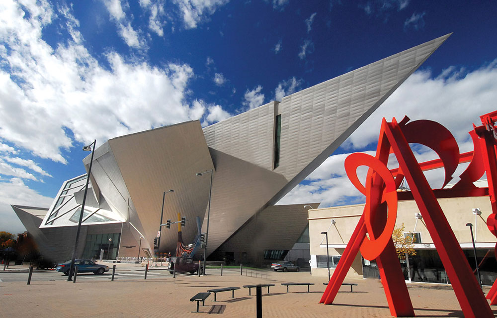 A red sculpture is displayed outside a metallic, silver building with many sharp angles in Denver, Colorado.