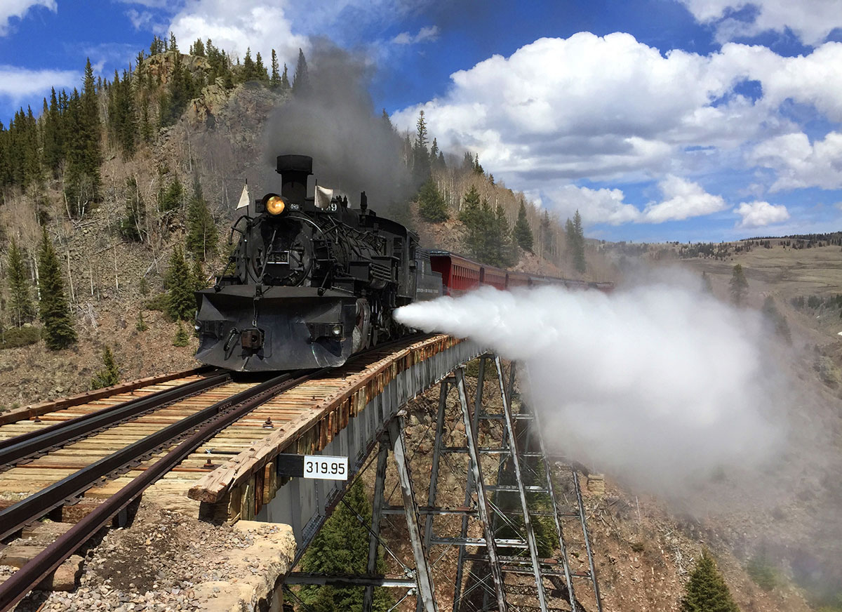 A train moves across a high mountain trestle