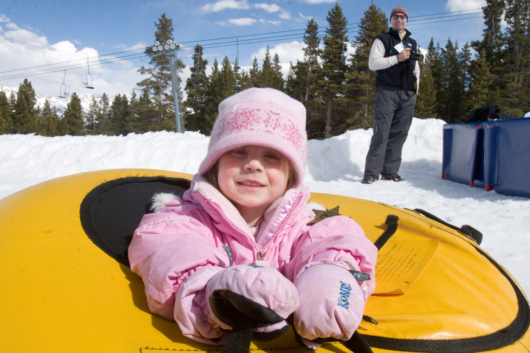 A young child smiles in a snow tube