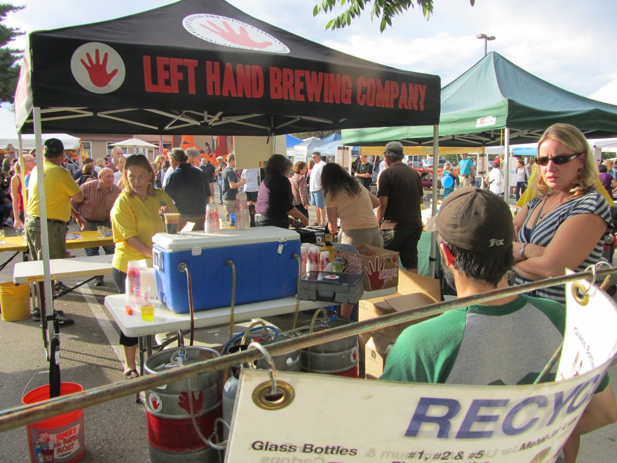People visit the Left Hand Brewing Company Tent that has a blue cooler on a white table with kegs in front of it at Niwot's Oktoberfest.