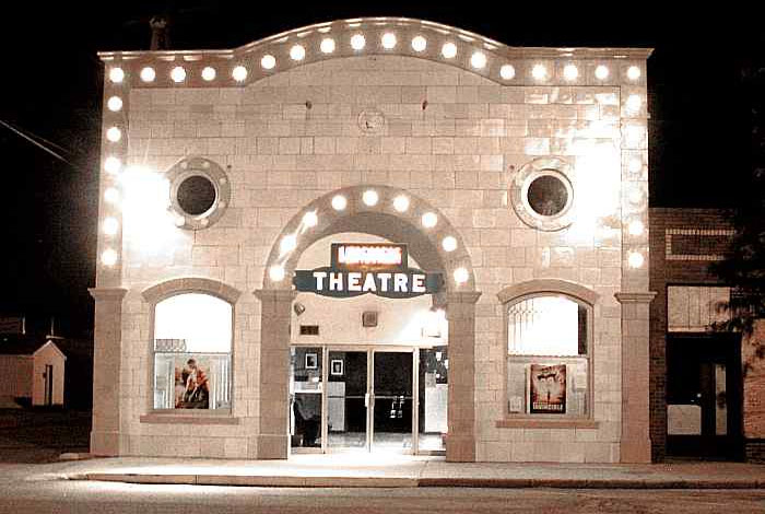 The stone-front of the historic Hippodrome Arts Centre at night. The sign says "Theatre" in between an arched entrance.