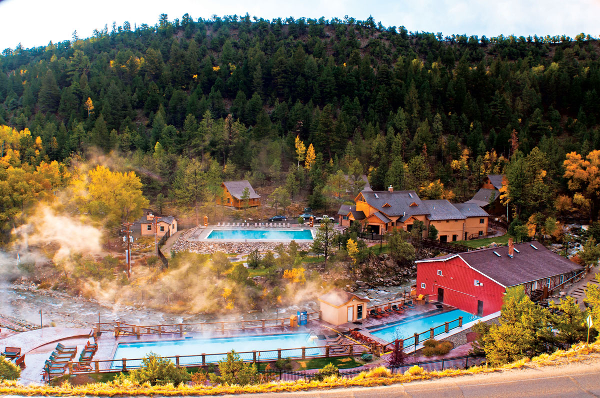 Fall colors begin to show in the foliage around Mount Princeton Hot Springs Resort in Colorado. Steam billows up and drifts away from the toasty hot spring pools.