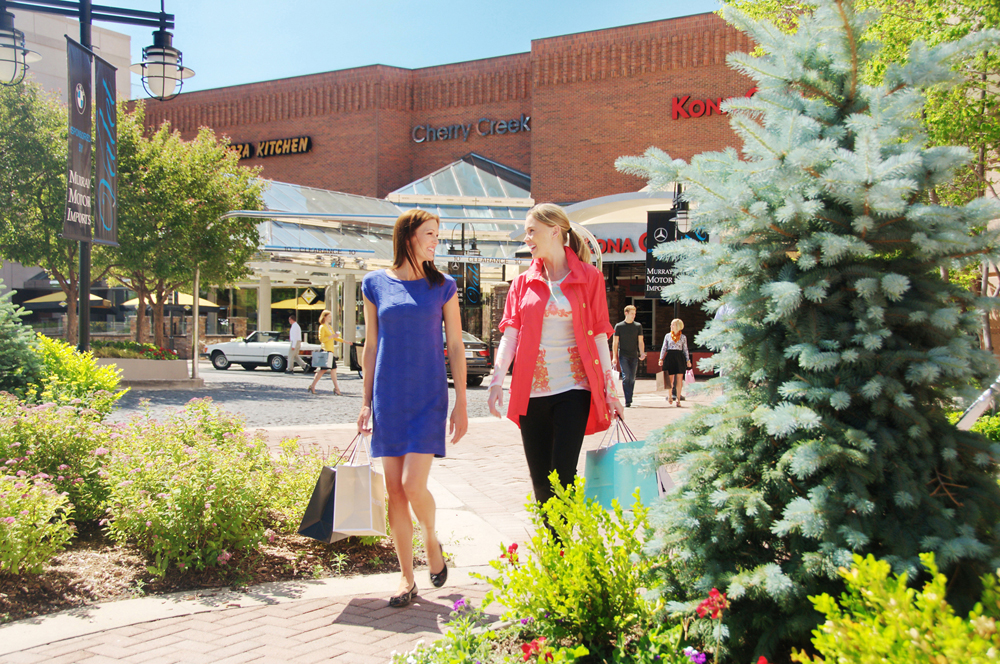 Two women are shopping with stores in the background