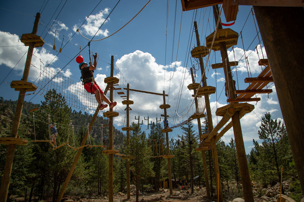 A person climbs ropes on an obstacle course high in the air at Colorado Adventure Center in Idaho Springs, Colorado.