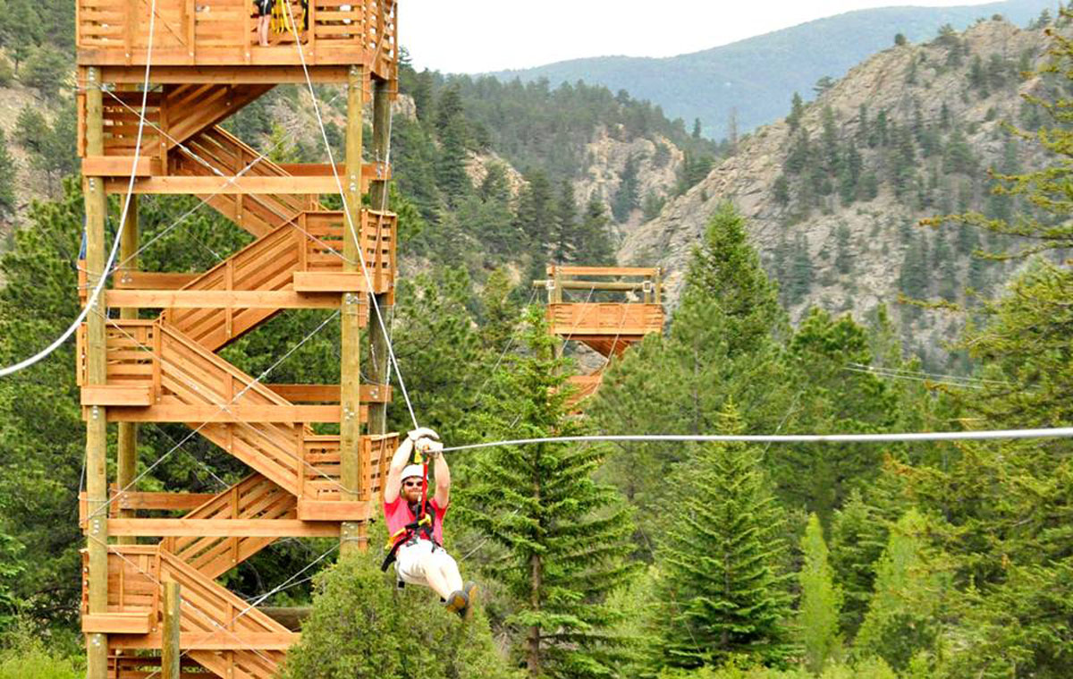 A person whizzes across a zipline cable from a tower at Colorado Adventure Center in Idaho Springs, Colorado.