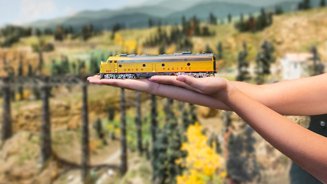 Outside the Colorado Model Railroad Museum in Greeley, a child lays a small, aspen-gold model of the Union Pacific train across their hands and an arm.